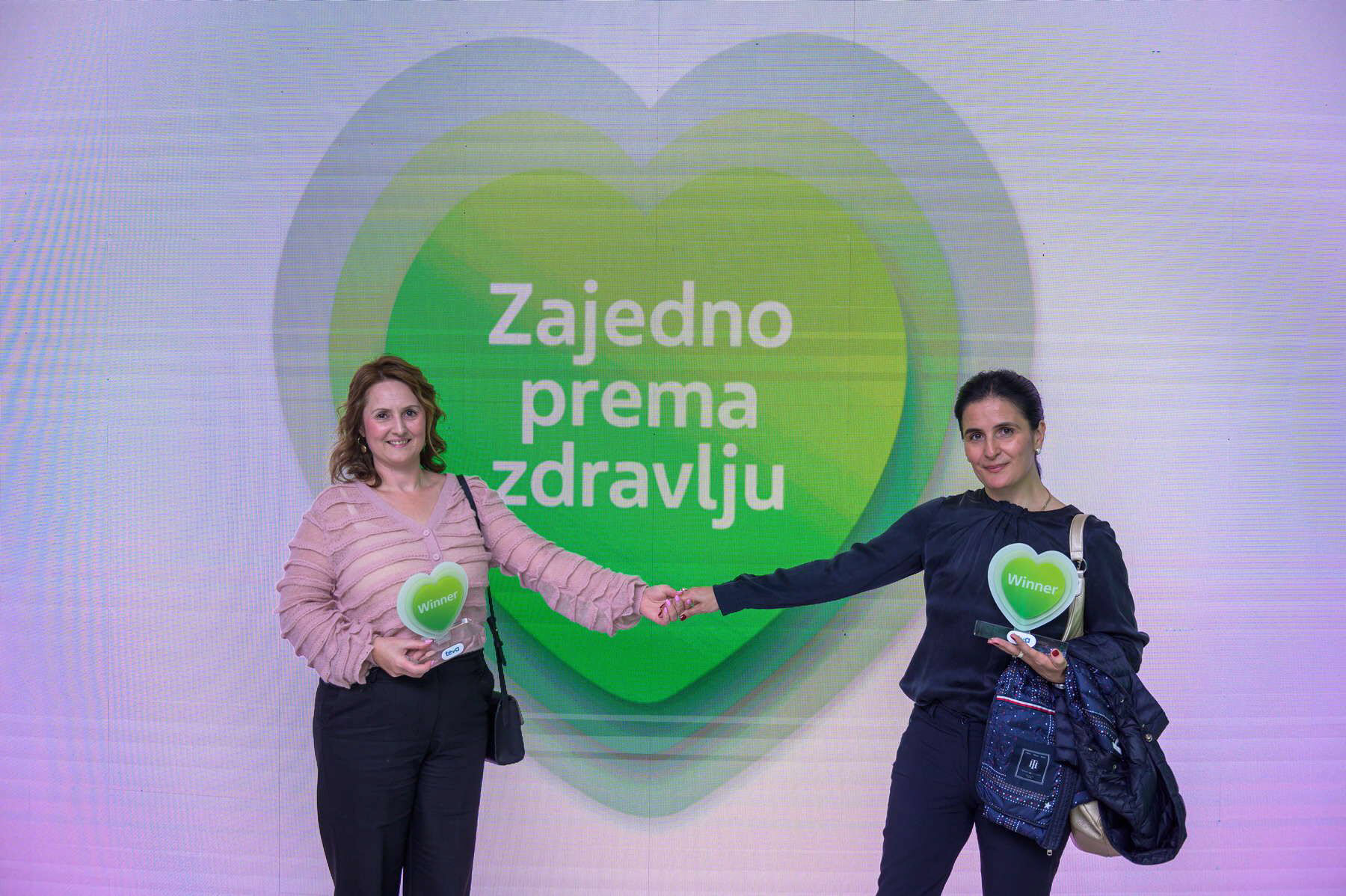 Winners holding hands in front of logo