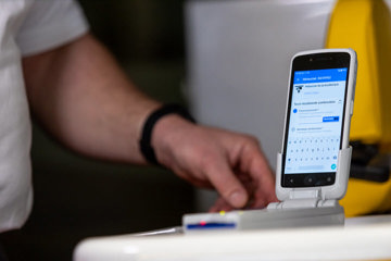 A person interacts with a smartphone mounted on a white stand