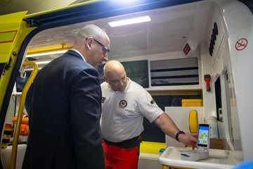 Two men in an ambulance looking at a mobile device