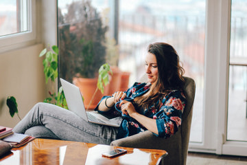 Girl drinking coffee and looking at a laptop