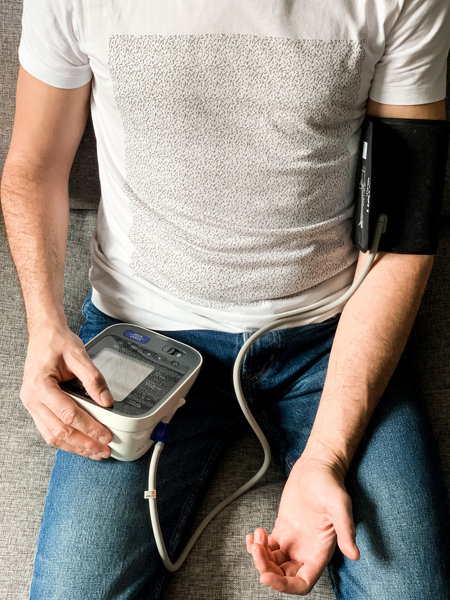 man checking blood pressure at home sitting on couch