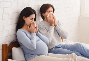 Man and pregnant woman sneezing