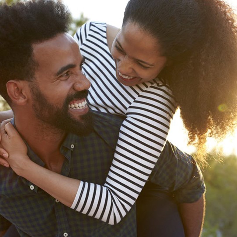Young woman piggyback riding bearded man