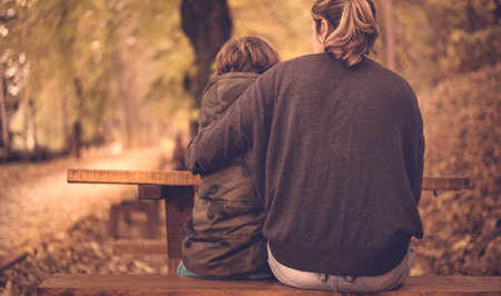 A mother hugging her daughter on a bench
