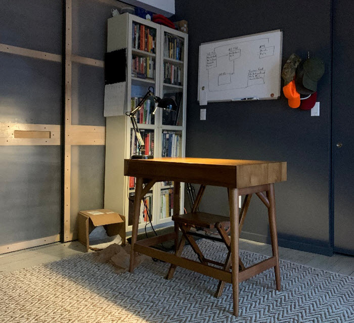 A room featuring a desk, chair, and bookshelf.