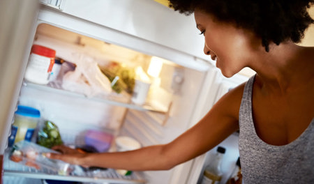 A woman grabbing something from her fridge