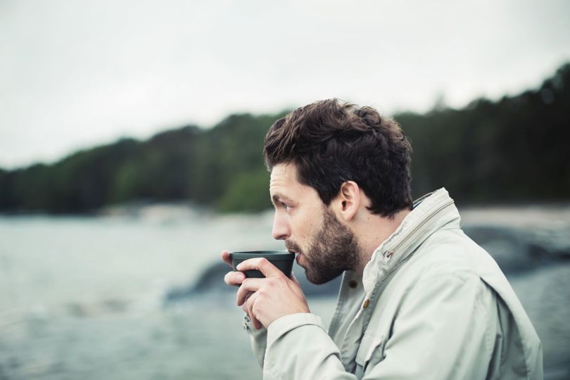 Man drinking from cup at the beach
