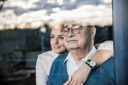 Woman and old man looking through a window