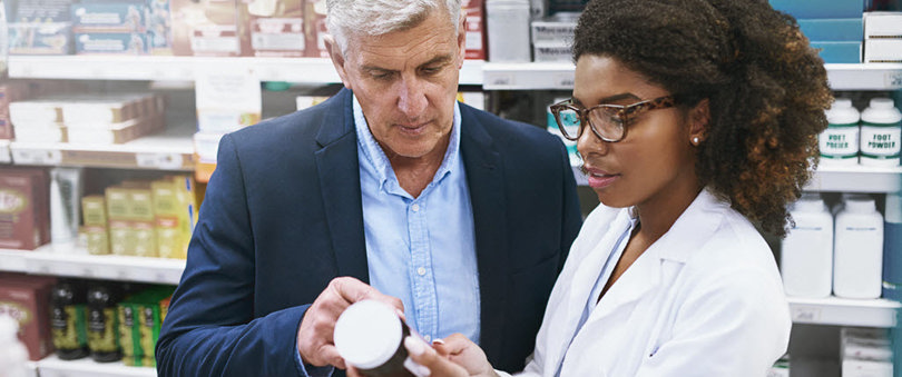 Pharmacist and man looking at medicine