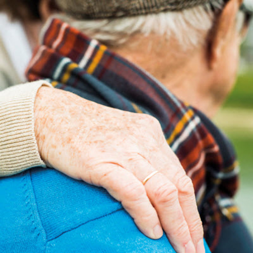An elderly man with a hand around his shoulder