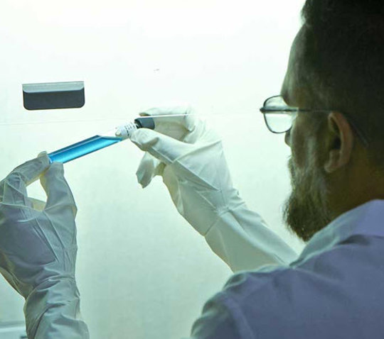 Scientist holding a blue vial