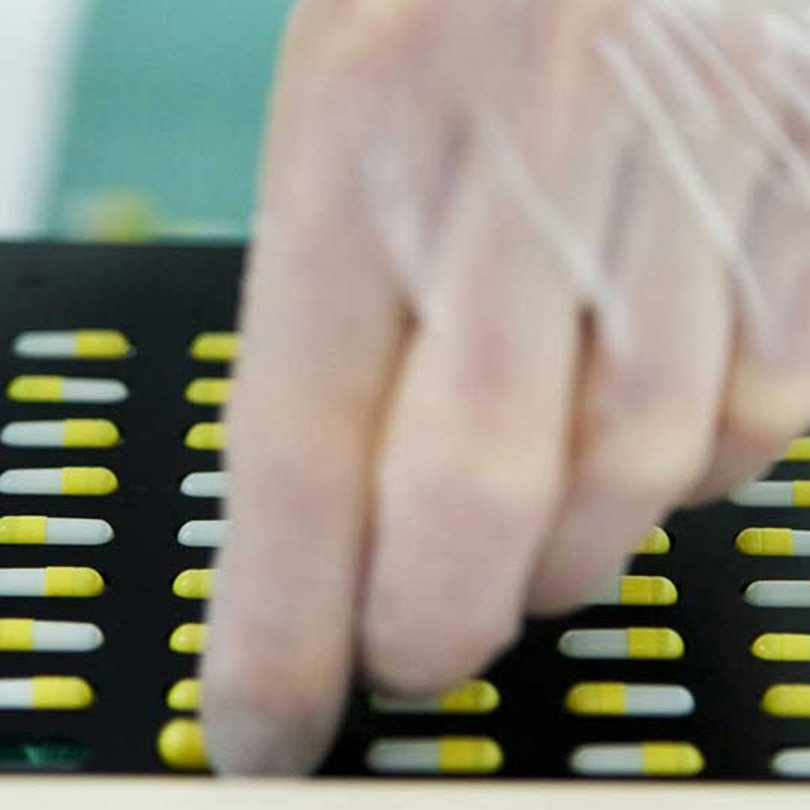Gloved hand sorting pills.