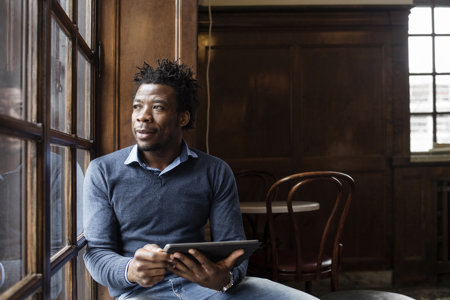 Man sitting next to a window, looking outside.